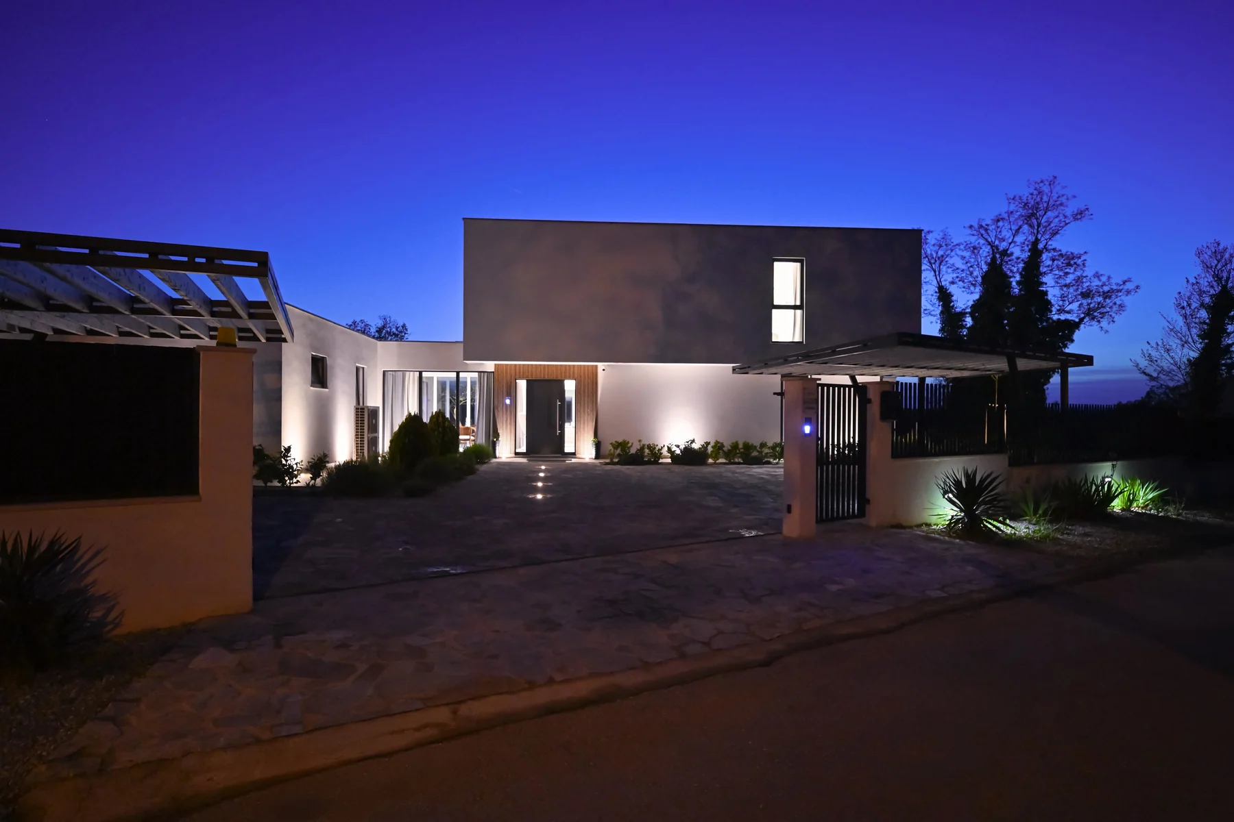 Modern luxury residence illuminated against an evening sky